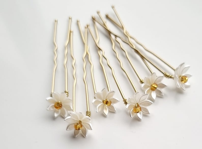 May include: Set of ten gold hair pins with white flower accents and a yellow center bead.
