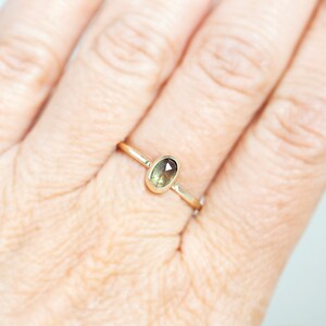 May include: A gold ring with a light green oval-shaped gemstone.