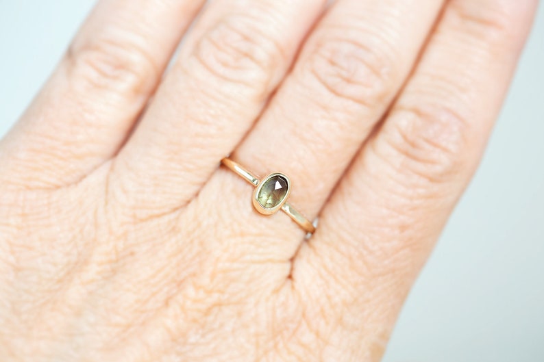 May include: A gold ring with a light green oval-shaped gemstone.