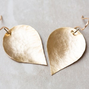 May include: A pair of gold-toned teardrop-shaped earrings with a hammered texture.