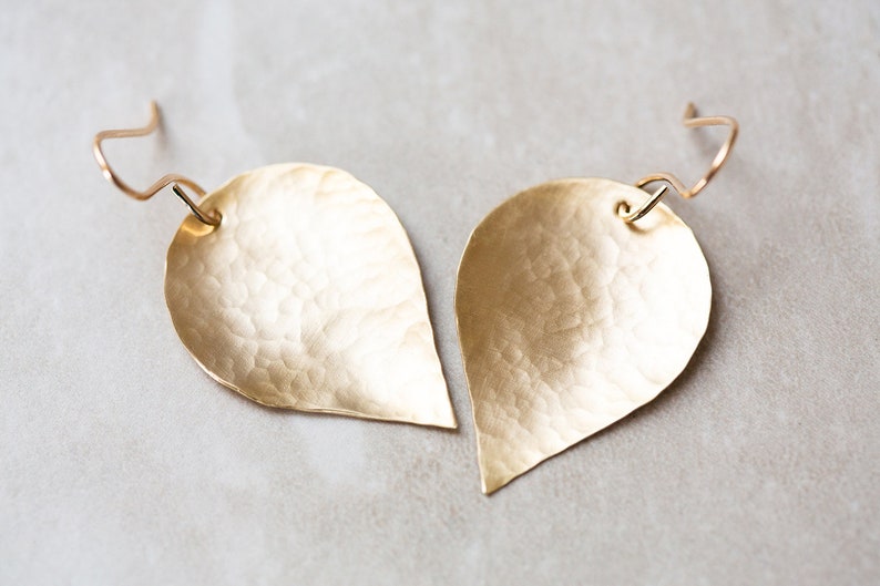 May include: A pair of gold-toned teardrop-shaped earrings with a hammered texture.