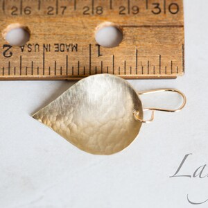 May include: A gold teardrop-shaped earring with a hammered texture. The earring is approximately 1 inch long and is shown next to a ruler. The word "Large" is written below the earring.