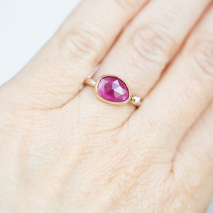 May include: A gold ring with a large, oval-shaped pink gemstone and a smaller diamond accent.