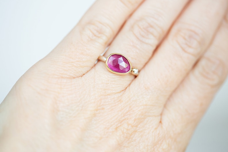 May include: A gold ring with a large, oval-shaped pink gemstone and a smaller diamond accent.