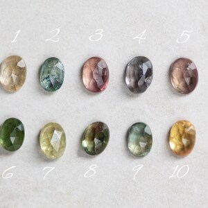 May include: Ten oval-shaped gemstones in various shades of green, yellow, and pink. The gemstones are numbered 1 through 10.