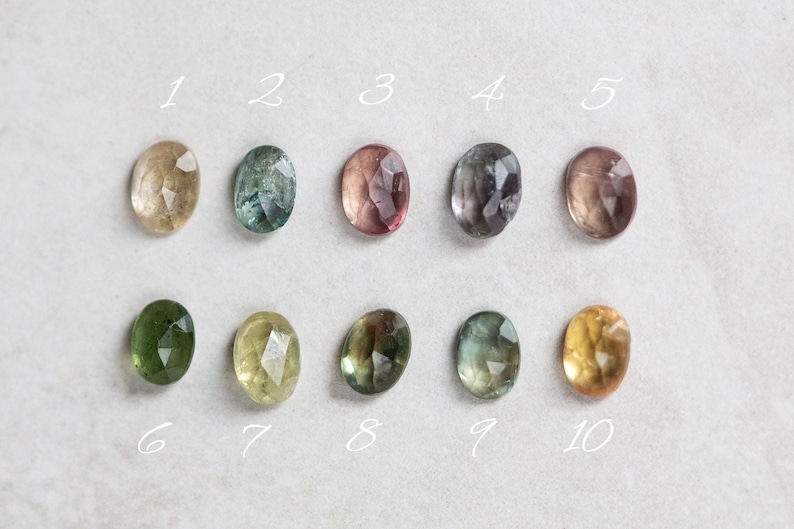 May include: Ten oval-shaped gemstones in various shades of green, yellow, and pink. The gemstones are numbered 1 through 10.