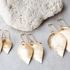 May include: Three pairs of gold leaf-shaped earrings with hammered textures. The earrings are of different sizes.