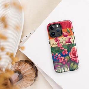 Pode incluir: Uma capa de telefone colorida com um design floral. A capa apresenta um padrão de listras arco-íris com flores rosa, vermelhas, laranja, amarelas, verdes, azuis e roxas.