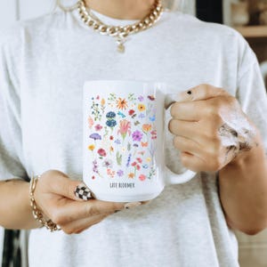 May include: White ceramic mug with a floral design and the text "Late Bloomer". The mug is filled with colorful flowers, including pink, purple, blue, yellow, and red.