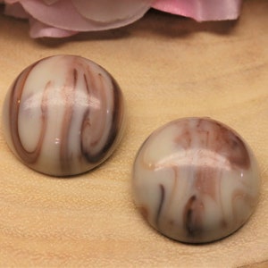 May include: A pair of round, cream-colored earrings with brown marbling. The earrings are smooth and glossy.