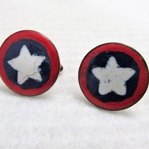 Può includere: Un paio di gemelli con un design a stella rosso, bianco e blu. La stella è bianca con un contorno blu ed è centrata su un cerchio blu con un anello esterno rosso.