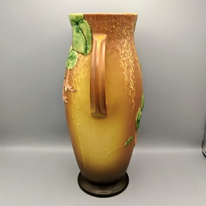 Może przedstawiać: Brązowy i ż&oacute;łty ceramiczny wazon z kwiatowym wzorem i dwoma uchwytami. Wazon ma fakturowaną powierzchnię i brązową podstawę.