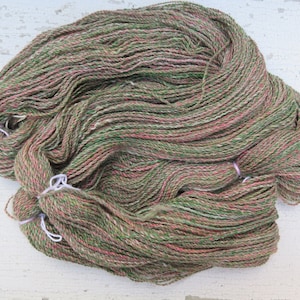 May include: A skein of yarn in shades of green, pink, and white. The yarn is made of natural fibers and has a soft, fuzzy texture.