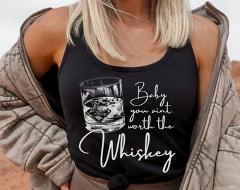 May include: Black tank top with a whiskey glass graphic and the text "Baby you ain't worth the Whiskey" in white script. The top is a casual style, suitable for everyday wear.