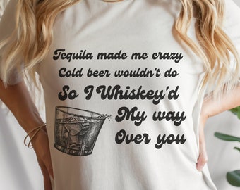 May include: White t-shirt with black text that reads "Tequila made me crazy Cold beer wouldn't do So I Whiskey'd My way Over you". A black and white illustration of a glass of whiskey with ice is next to the text.
