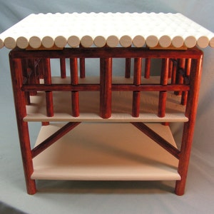 May include: A two-tiered wooden table with a white slatted top and red stained frame. The table has a simple design with a rectangular top and two shelves.