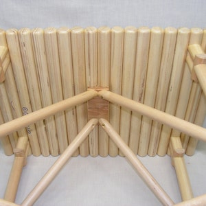 May include: A wooden stool with a slatted top and a triangular base. The stool is made of natural wood and has a rustic look.