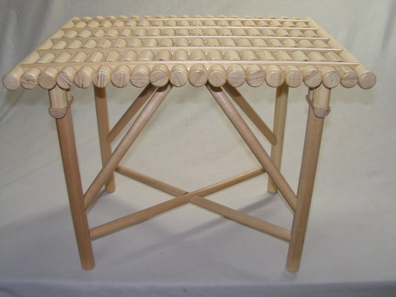 May include: A light wood folding stool with a slatted top made of round wooden dowels.