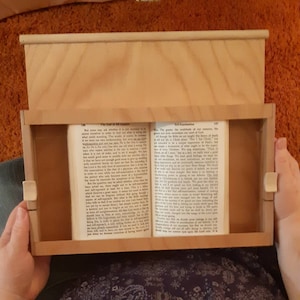 May include: A wooden book stand with a book open inside. The book is titled "The Chief of All Creation" and "Old Examination".