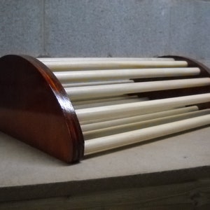 Peut inclure: Un repose-pieds en bois avec une forme incurvée et une série de lattes. Le repose-pieds est teinté d'une couleur brun foncé.
