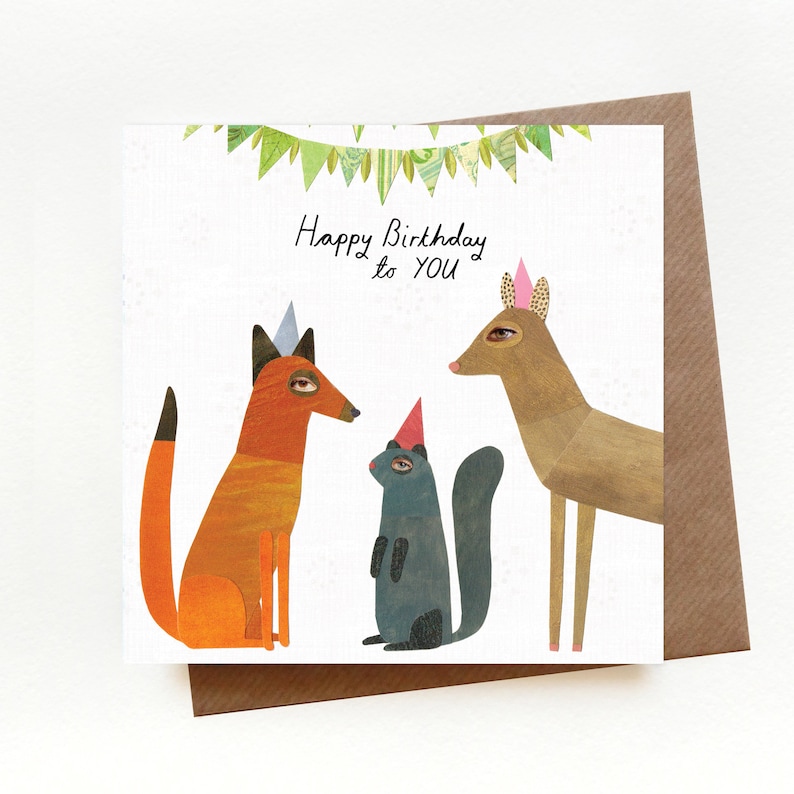 Puede incluir: Una tarjeta de cumplea&ntilde;os con un zorro, una ardilla y un ciervo que llevan sombreros de fiesta. La tarjeta tiene una guirlande verde con banderas y el texto "Happy Birthday to YOU".