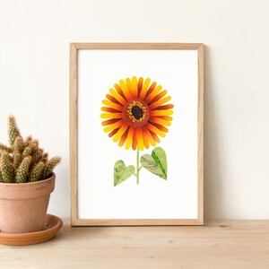 Puede incluir: Una impresión enmarcada de un girasol con pétalos naranja y amarillos y un centro marrón. El girasol tiene dos hojas verdes.