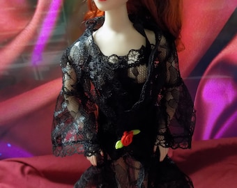 May include: A porcelain doll with red hair wearing a black lace dress with a red rose accent. The doll is standing on a black base with the word "Madrid" written on it.