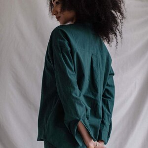 May include: A dark green long-sleeved shirt with a collared neckline. The shirt is made of a soft, comfortable fabric and has a relaxed fit.