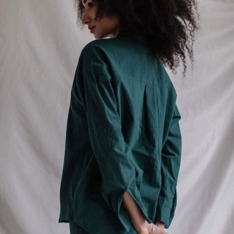 May include: A dark green long-sleeved shirt with a collared neckline. The shirt is made of a soft, comfortable fabric and has a relaxed fit.