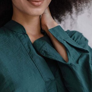 May include: A teal green collared shirt with long sleeves and a V-neck.