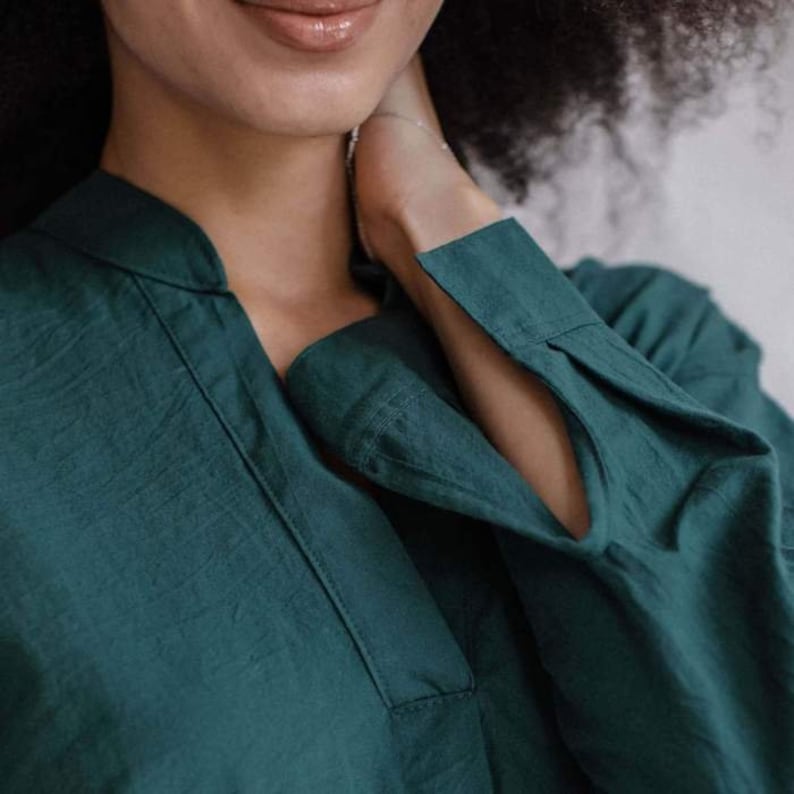 May include: A teal green collared shirt with long sleeves and a V-neck.