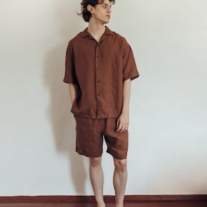 May include: A person wearing a brown linen short-sleeved shirt and matching shorts. The shirt has a collar and button closure.