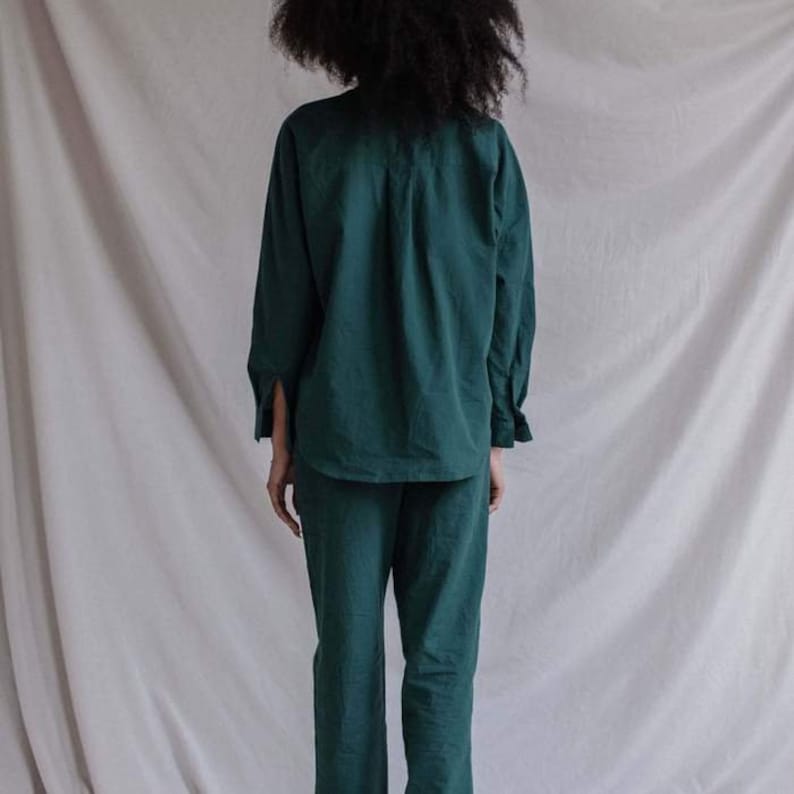 May include: A dark green long-sleeved shirt and matching pants. The shirt has a collared neckline and button closure. The pants have a straight leg.