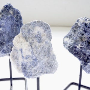 May include: Three blue and white natural stone pieces on black metal stands. The stones are rough and have a natural, organic look.