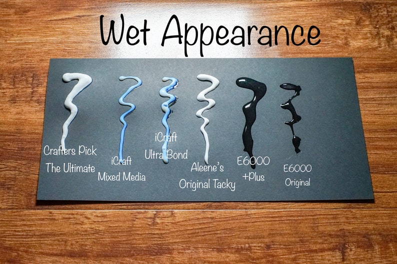 May include: A black card displays samples of various adhesives, showcasing their "Wet Appearance." The samples include Crafters Pick, iCraft, Aleene's, and E6000, each in a unique wavy pattern. The text "Wet Appearance" is at the top.