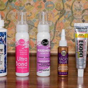 May include: Assortment of craft adhesives in various containers. Includes bottles of "Crafter's Pick The Ultimate!", "iCraft Ultra Bond Adhesive", "iCraft Mixed Media Adhesive", "Aleene's Original Tacky Glue", "E6000 Plus", and "E6093".
