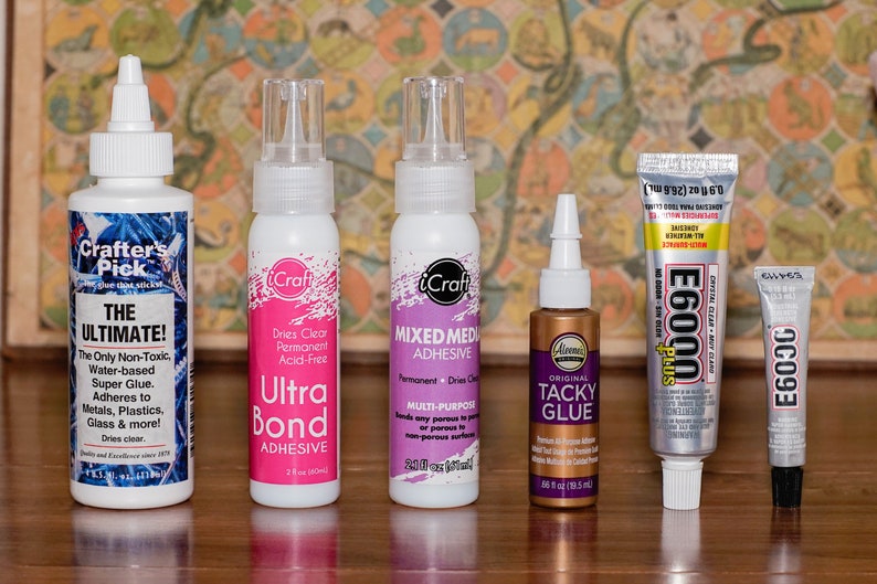 May include: Assortment of craft adhesives in various containers. Includes bottles of "Crafter's Pick The Ultimate!", "iCraft Ultra Bond Adhesive", "iCraft Mixed Media Adhesive", "Aleene's Original Tacky Glue", "E6000 Plus", and "E6093".