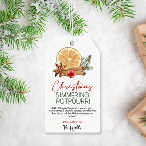 May include: A white gift tag with a red and green Christmas-themed design. The tag features a handwritten title "Christmas Simmering Potpourri" and instructions for making the potpourri. The tag also includes a handwritten note "Homemade by: The Halls".