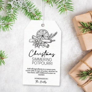 Może przedstawiać: Biała etykieta prezentowa z czarno-białym rysunkiem przepisu na świąteczny potpourri do gotowania. Etykieta zawiera tekst "Christmas Simmering Potpourri" oraz instrukcje dotyczące przygotowania potpourri. Tekst "Homemade by: The Halls" znajduje się na dole etykiety.