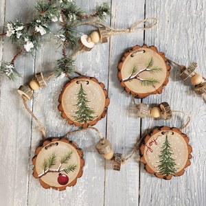 May include: A rustic Christmas garland with four wooden ornaments painted with pine trees and snow. The ornaments are strung together with twine and wooden beads. One ornament has the word "Joy" painted on it.