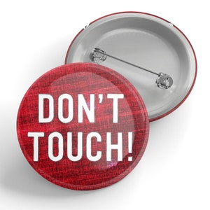 May include: Red button with white text that reads "DON'T TOUCH!" The button has a textured surface that resembles burlap.