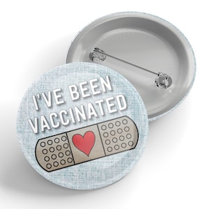 May include: A blue button with a white bandage and red heart design. The text "I've Been Vaccinated" is printed on the button.