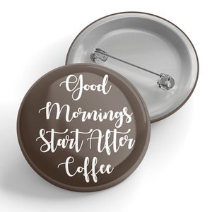 May include: A brown button with the text "Good Mornings Start After Coffee" in white script. The button has a pin back and a silver metal rim. The second button is visible in the background.