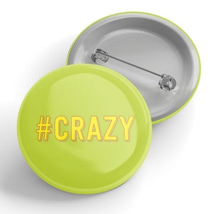 Könnte beinhalten: Ein limegrüner Knopf mit einem gelben Hashtag und dem Wort "CRAZY" in Gelb.