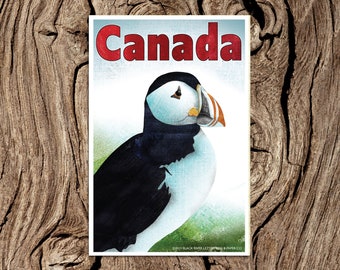 May include: A vintage-style postcard featuring a colorful illustration of a puffin with the word "Canada" in red lettering.