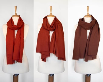 May include: Three brown scarves displayed on mannequins. The scarves are made of a soft, woven fabric. The scarves are displayed in different ways, showing the versatility of the fabric.