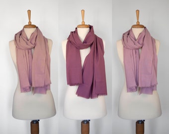 May include: Three mannequins wearing different shades of pink scarves. The scarves are made of a soft, lightweight fabric and have a fringed edge.