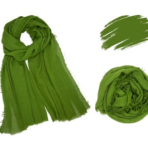 May include: A green scarf made of a soft, textured fabric. The scarf is shown laid out flat and rolled up.