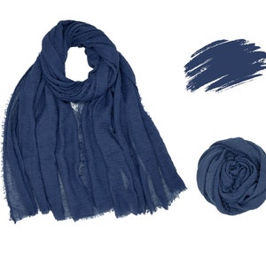May include: A navy blue scarf with a fringed edge is displayed, along with a swatch of the same color and a rolled-up scarf. The scarf is made of a soft, lightweight fabric.