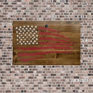 May include: A distressed wooden American flag with red, white, and blue paint. The flag is mounted on a brick wall.